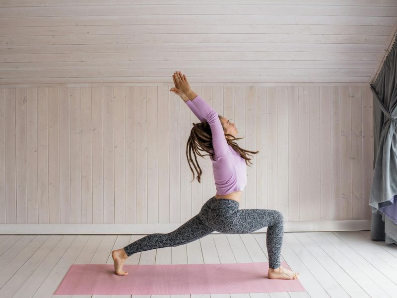 Detailed view of a person performing a yoga sequence in a sunlit room.